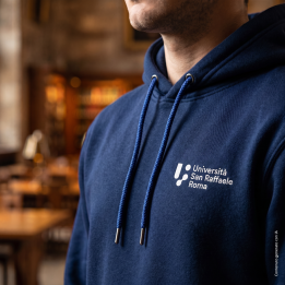 Men's navy blue hoodie worn, close-up of the chest logo — lifestyle photo